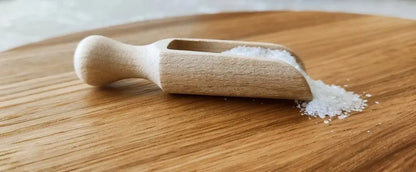 Hand washing a wooden spice spoon under warm water with a soft sponge.
